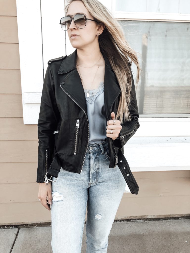Biker jacket paired with satin cami, jeans, and black booties. 
